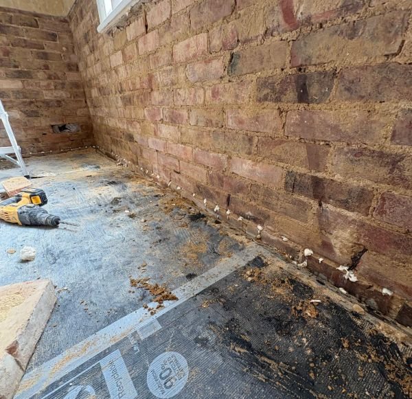 Masonry wall hacked back to brick ready for damp-proof course injection