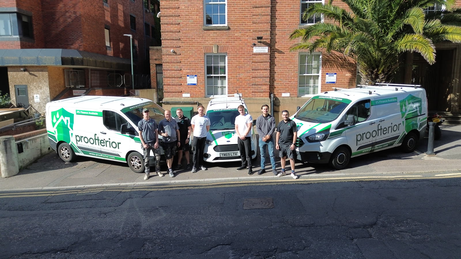 The Proofterior team standing with branded vans
